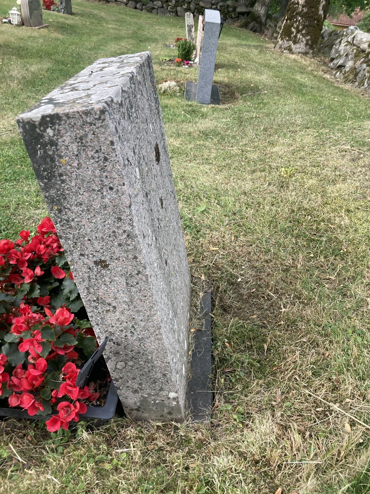 Gravsteinen sett fra siden før arbeidet, tydelig hellende forover og med lav over toppen og sidene.